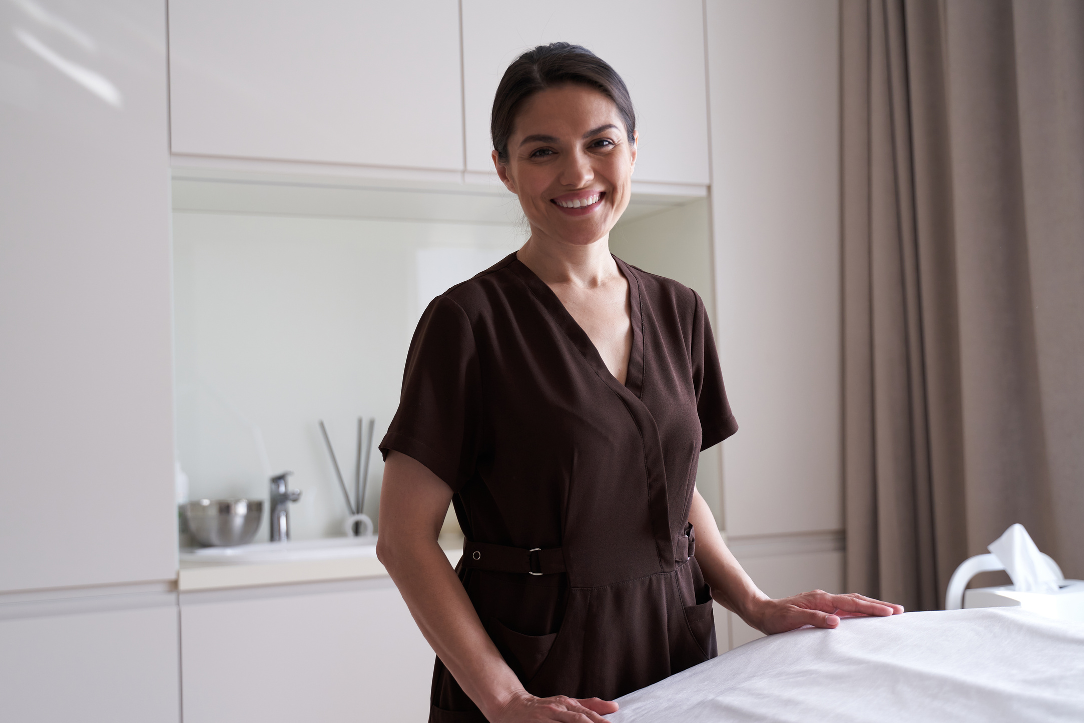 Happy pretty young female masseur standing in massage parlor